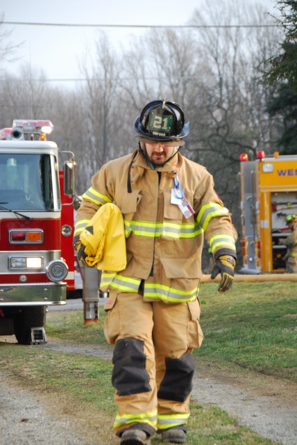 Firefighter Robert Bishop carrying a salvage cover at a house fire.