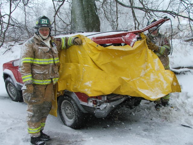 Firefighters Alan Hastings and Scott Wisner providing a shelter from the wind as EMS crews tend to a patient.