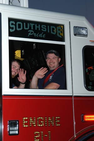 Firefighters Shaun Burke and Bucky Leonardi on Engine 1 in a parade.