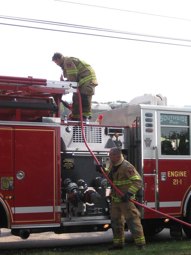 Firefighters Andy McCullin and Bill Hirthler racking the booster line on Engine 1.