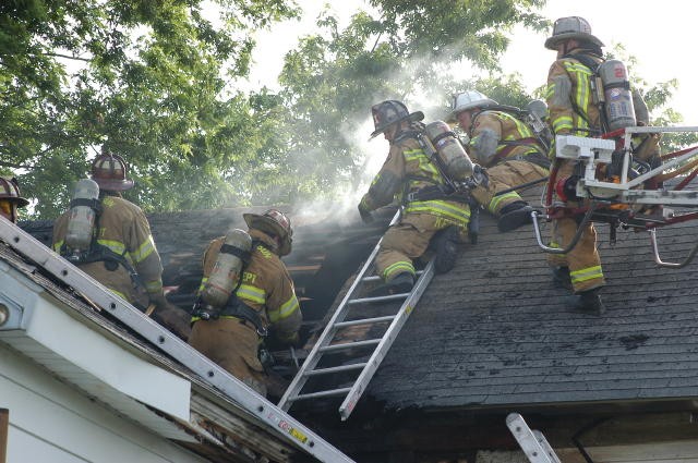 Oxford and Rising Sun crews opening a roof at a house fire on the state line.