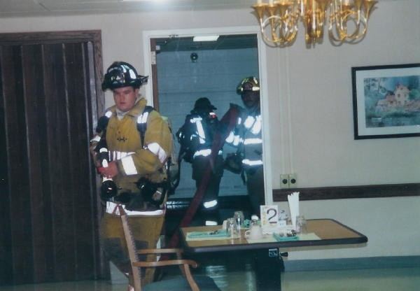 Firefighter Lonz Brown stretching a line through a dining room at the Ware.